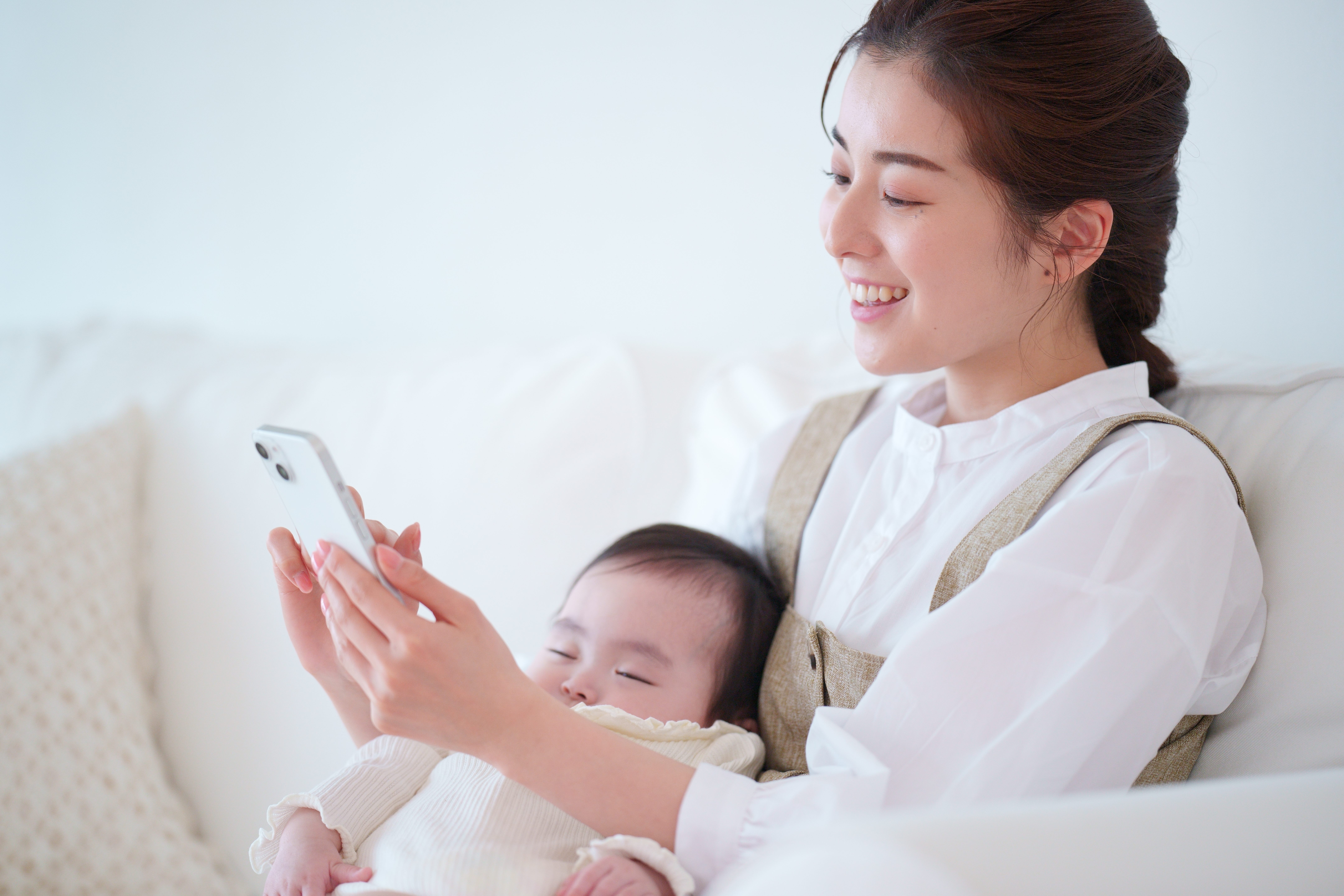 赤ちゃんを抱きながらスマホで相談する女性